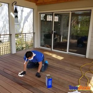 A TrueDecks worker paints a deck